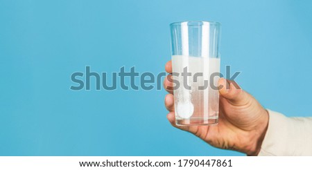 Close up of man holding a pill. Glass of water tablet. Glass with efervescent tablet in water with bubbles.