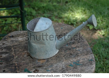 Old watering can on a wood stool