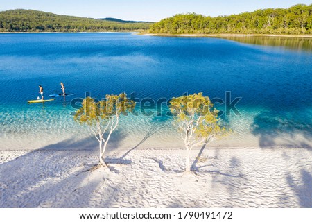 Couple stand up paddle boarding  on Lake Mckenzie, Fraser Island, Queensland, Australia Royalty-Free Stock Photo #1790491472