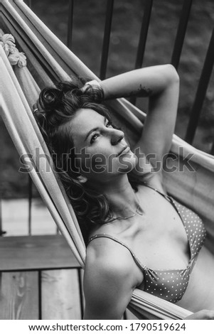young beautiful woman lies in a hammock and drinks champagne from a glass. Black and white photo portrait close-up.