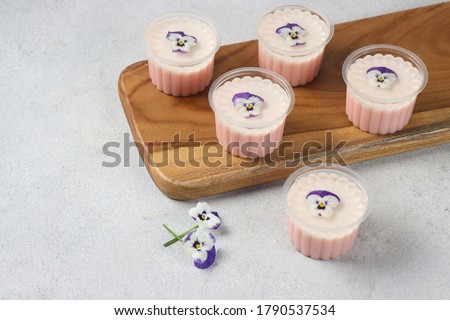 Puding bunga gelas. Edible flower pudding cup. On the top side, clear pudding with edible flower, Middle part is milk flavor and the bottom side is red velvet flavor.