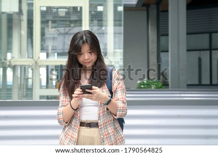 Asian woman surfing cellphone. Urban setting.