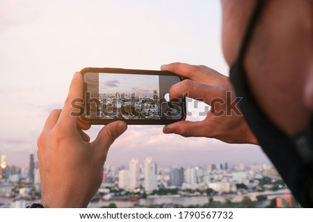 man take pictures of the buildings in the city. Sunrise time He uses a high-angle recording photo phone. concepts  technology