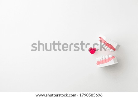 Teeth model and heart shaped capsule on white background
