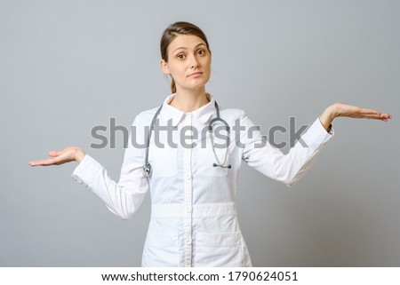 Portrait of woman doctor shrugging shoulders isolated on gray background