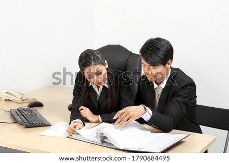 Young Asian male female wearing suit sitting at office desk thinking meeting disucsing sign document agreement