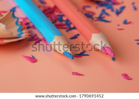 Blue and pink pencils. Colored wooden and graphite pencils shavings on pink surface. Macro.
