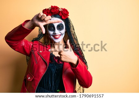 Woman wearing day of the dead costume over yellow smiling making frame with hands and fingers with happy face. creativity and photography concept. 