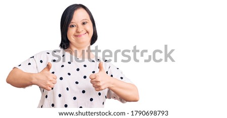 Brunette woman with down syndrome wearing casual clothes success sign doing positive gesture with hand, thumbs up smiling and happy. cheerful expression and winner gesture. 