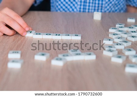 children make up the word school from letters on a wooden table, the concept of the beginning of the school year, homework, lessons, back to school
