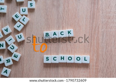 children make up from letters on a wooden table the words back to school, the concept of the beginning of the school year, homework, lessons