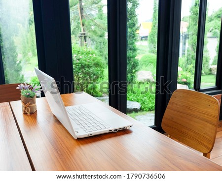 A laptop on the wooden table in the living room near to the garden. Royalty-Free Stock Photo #1790736506