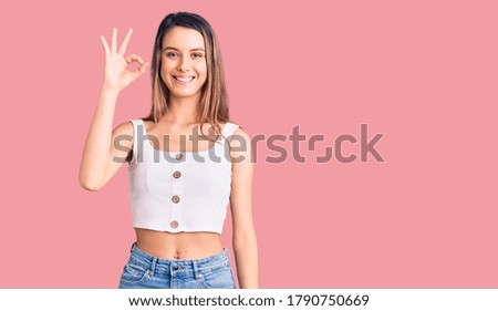 Young beautiful girl wearing casual sleeveless t shirt smiling positive doing ok sign with hand and fingers. successful expression. 