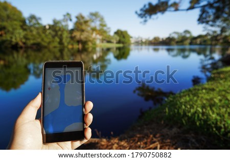 Man using mobile map app next to the lake. Smartphone with 5g connection Royalty-Free Stock Photo #1790750882