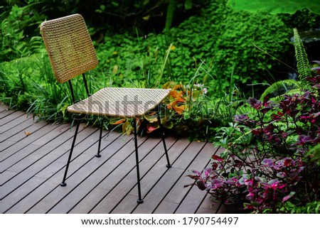 chair in a garden on wood floor with beautiful tree and flowers in the garden