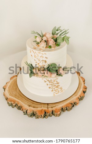 White wedding cake with flowers and greenery on wood