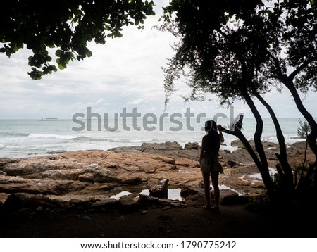 Samed, Thailand. Silhouette of Asian woman traveler by rock beach looking away.  