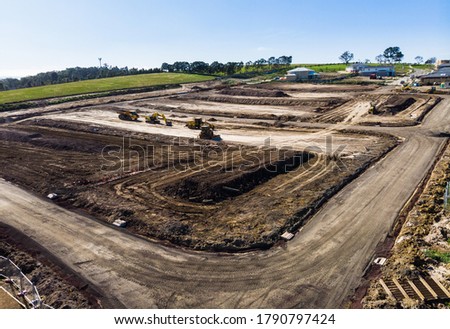On the outskirts of Melbourne Australia, a new estate is in the early stages of construction, heavy machinery terraforms the hillside, roads are being built and drainage installed before houses arrive Royalty-Free Stock Photo #1790797424