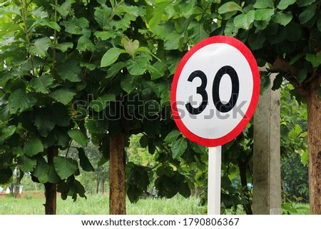 Road sign speed limit, 30 mph, on a road. Transportation and sign concept.