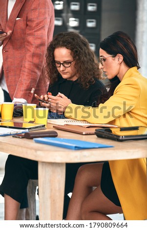 Smiling businesswoman smiling with telephone in a meeting with her colleagues working in the background