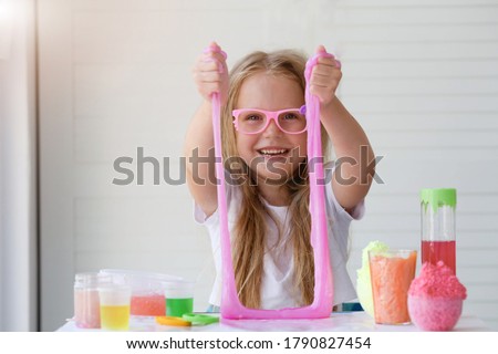  Little girl stretching pink slime to the sides. Kids hands playing slime toy. Making slime. Copyspace.  Royalty-Free Stock Photo #1790827454