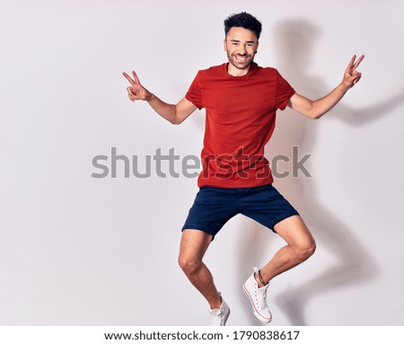 Young handsome man wearing casual clothes smiling happy. Jumping with smile on face doing victory sign over isolated white background