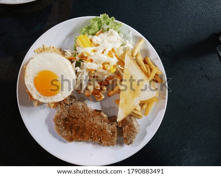 Beef steak, American fried rice, fried egg with salad, toast and french fries