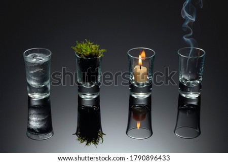 Four elements of nature - air, fire,  earth, water. Four elements concept in glasses on a black reflective background. Royalty-Free Stock Photo #1790896433
