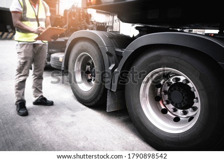 Semi truck, Maintenance and Vehicle inspection.  A truck mechanic driver holding clipboard, his safety checking a truck wheels and tires. Royalty-Free Stock Photo #1790898542