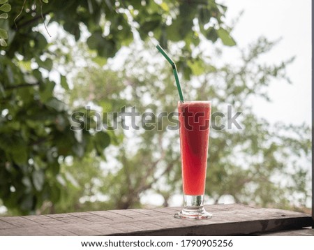 a glass of watermelon juice on table bar with tropical background.