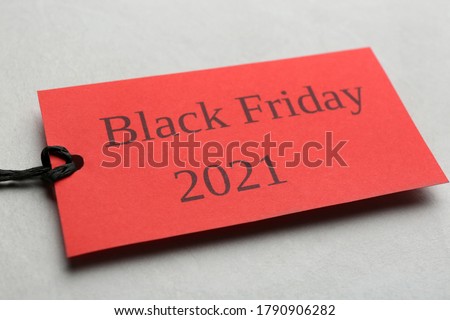 Red tag with words BLACK FRIDAY 2021 on light grey background, closeup