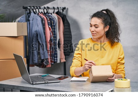Woman working from home, sending parcel, writing address on the package