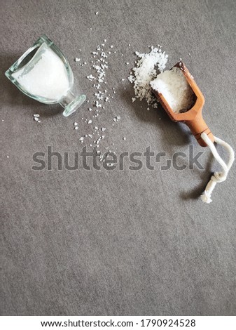 picture of a scoop and bottle of white bathsalt .