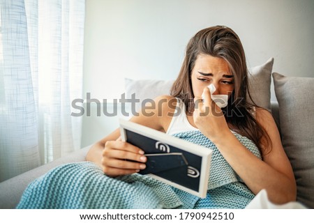 Broken woman heart in relationship concept. Cropped view of upset woman holding picture frame and crying at home. Upset woman looking at picture frame, crying and wiping tears at home