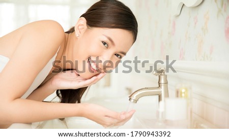 Beautiful woman washing hand and face in bathroom
