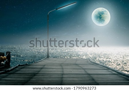The pier bridge looks at the full moon on a beautiful night.