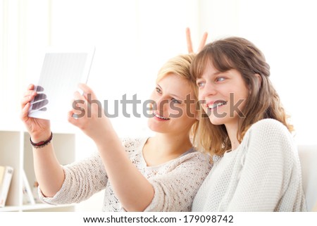View of Girls on sofa taking selfie picture with tablet