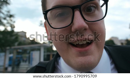 funny guy nerd in suit and glasses tells something to the camera very enthusiastically. Typical nerdy close-up face tells story.