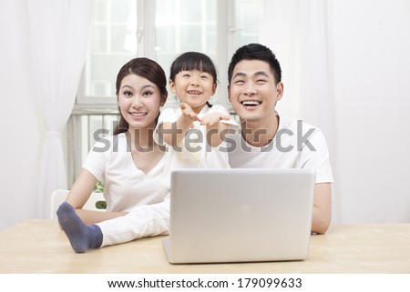 	Little girl using laptop with her parents	