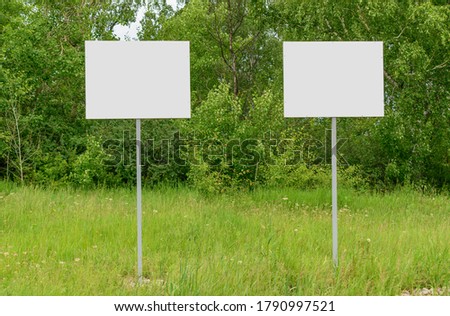 Two banners on a metal support. Green forest and grass. Concept - ad template, warning, comparison.