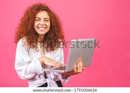Pretty young business woman in casual holding laptop, isolated over pink background. 