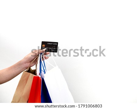 A picture of an isolate of a hand holding a black credit card and several paper bags  To submit payment