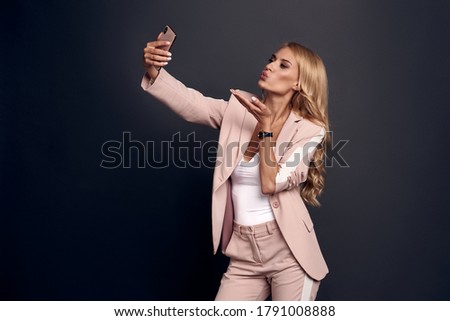 Portrait of cheerful wavy-haired lady taking making selfie isolated over grey background.