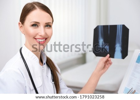 Professional orthopedist examining X-ray picture in her office