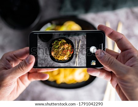 Photographing food. Hands taking photos of delicious vegetable noodles with smartphone