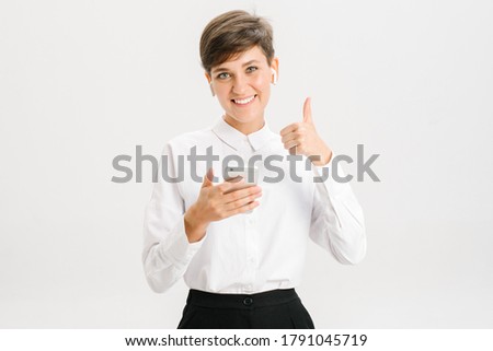  smiling woman uses wireless headphones for a video call and showing like. white background in studio. online business meeting concept. High quality photo