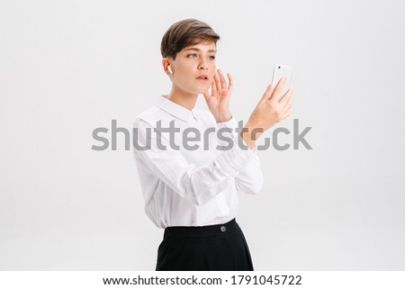 a young woman uses wireless headphones for a video call. white background in studio. online business meeting concept. High quality photo