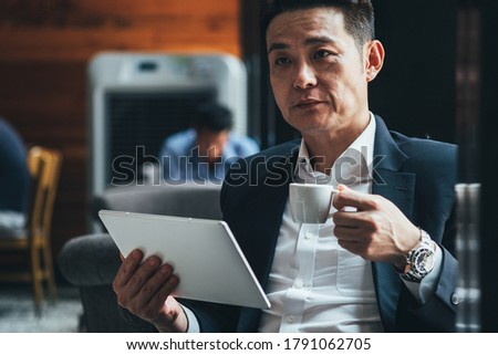 Serious business man drinking coffee and holding tablet stock photo