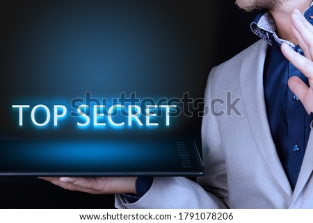 Businessman, man holds in his hand a tablet with a neon word, TOP SECRET text. Business concept.