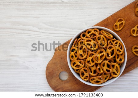 Crispy Pretzel Crackers in a Gray Bowl on a white wooden background, top view. Copy space.